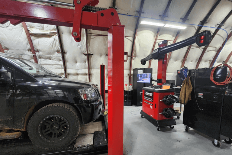 Wheel alignment service near me in Colorado Springs, CO with Legend Motor Works. Image of hunter wheel alignment machine attached to Black pickup truck in shop.